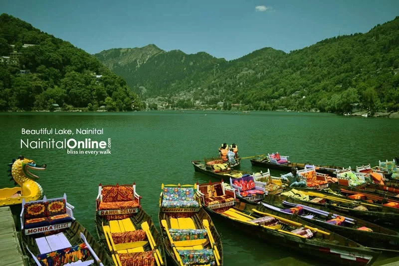 Colourful wooden boats on Naini Lake with wooded hills in the distance